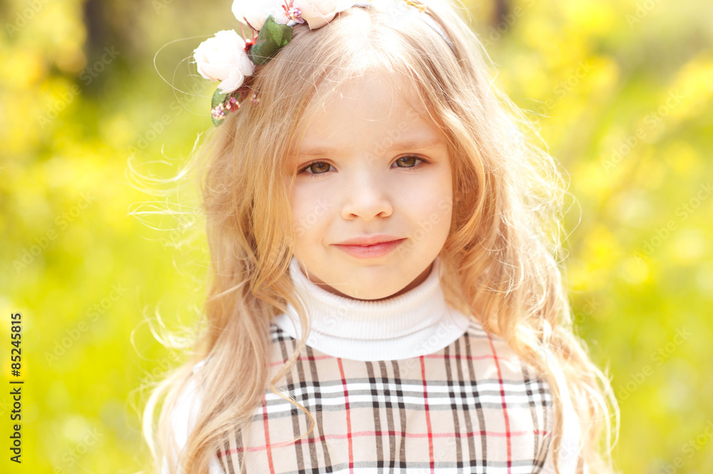 Smiling cute kid girl 3-4 year old wearing floral wreath over green nature background. Looking at camera. Childhood. Summer time. Smiling cute kid girl 3-4 year old wearing floral wreath over green nature background. Looking at camera. Childhood. Summer time.