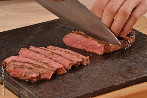 Φωτογραφία Cortando carne de ternera con un cuchillo,rebanabdo bistec a la Parrilla