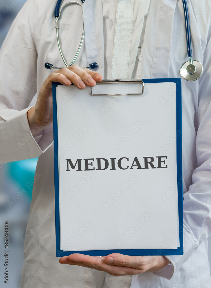 Doctor holds clipboard with medicare written Doctor holds clipboard with medicare written