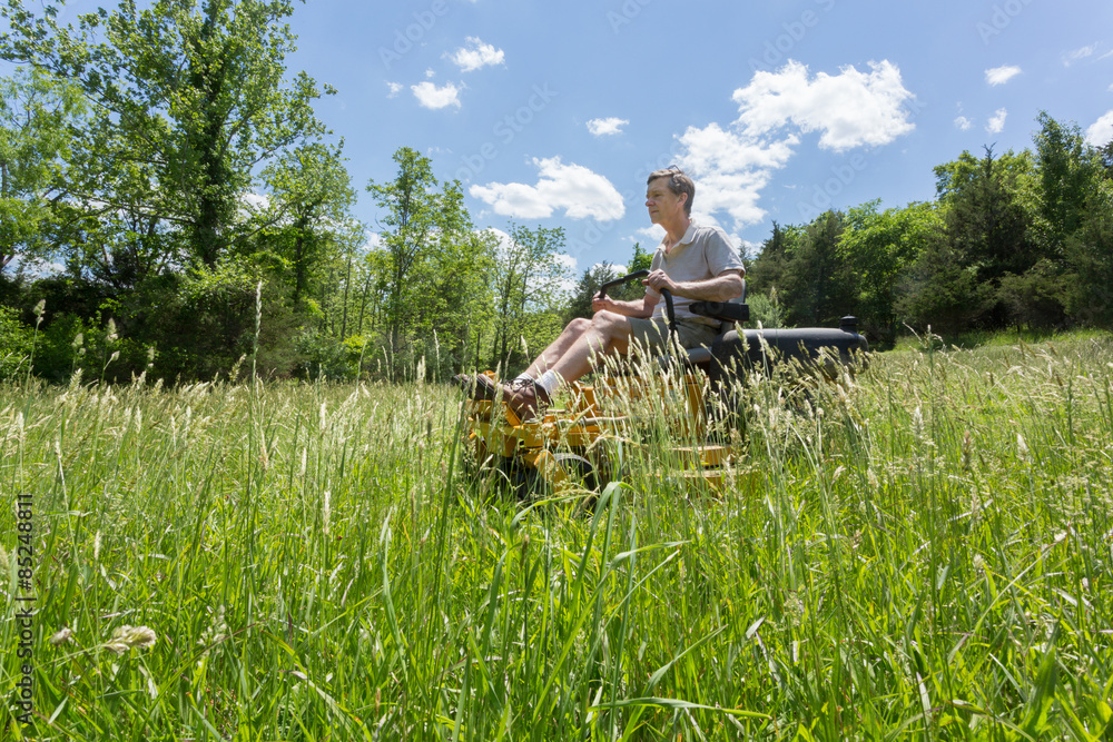 Obraz premium Senior man on zero turn lawnmower in meadow