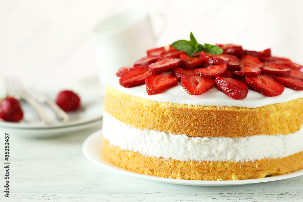 Sweet cake with strawberries on plate on white wooden background Sweet cake with strawberries on plate on white wooden background