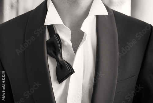 Obraz na plátně Close-up photo of man in tuxedo with open shirt and loose bow tie