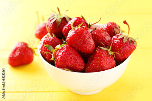 Strawberries berry in bowl on yellow wooden background