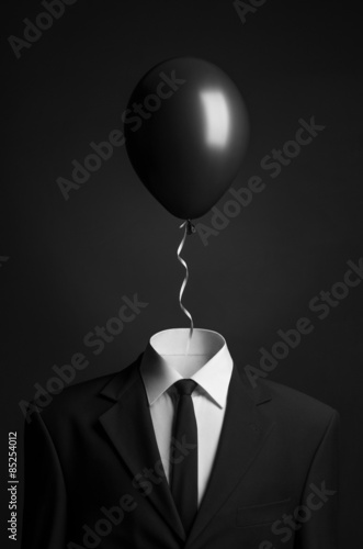Surrealism topic: balloon instead of a head on a man in a black suit on a black background