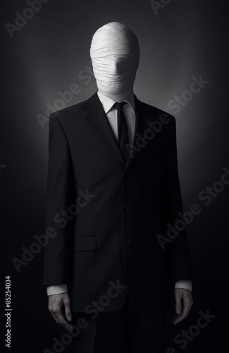 Internet meme and terrible character Halloween theme: very tall burly man with long arms in a suit with bandaged face fabric, an unknown killer in the suit, The Slender Man, Secret legend of the city