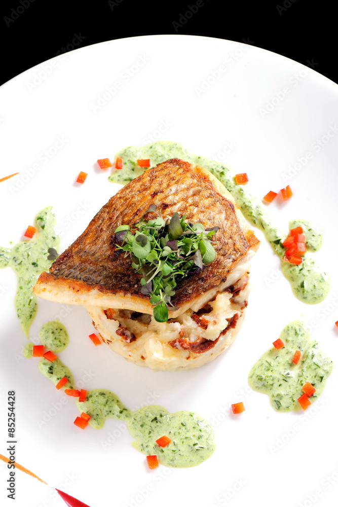Tasty healthy fish fillet with potato puree with dried tomatoes and wild garlic sauce