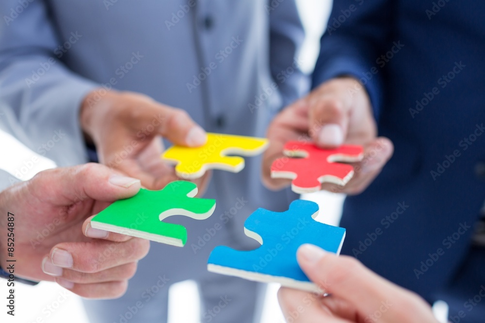 Business colleagues holding piece of puzzle Business colleagues holding piece of puzzle