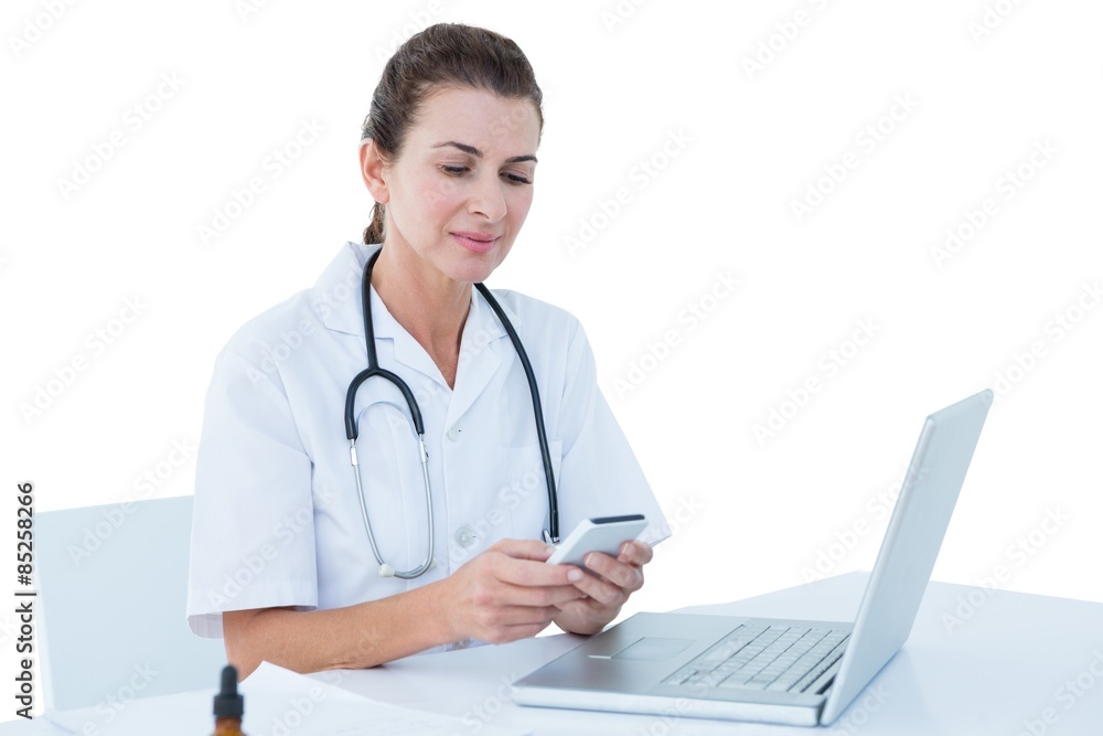 Doctor working on her laptop and her phone Doctor working on her laptop and her phone