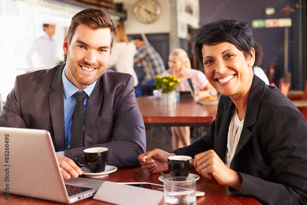 Two business people with laptop meeting in a coffee shop Two business people with laptop meeting in a coffee shop