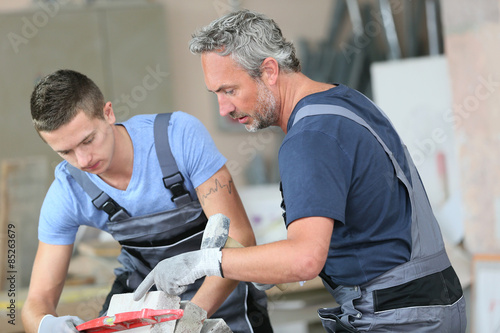 Teenager with professional brick layer in training school