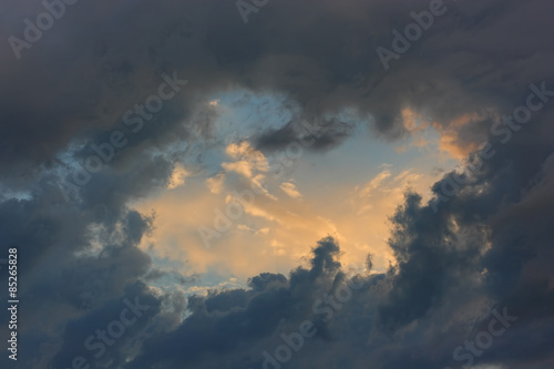 Dramatic cloudy sky. Dark heavy clouds after the rain has formed a divine gap of light and sun.