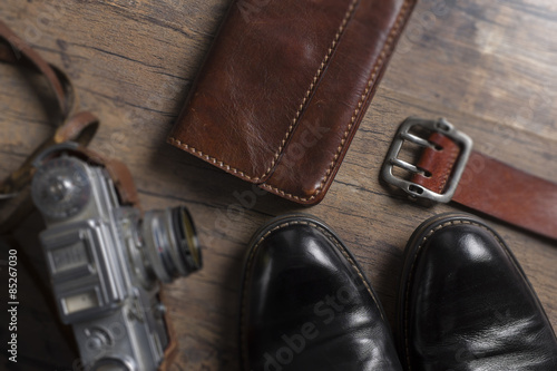 Black shoes, film camera and wallet on the wooden table