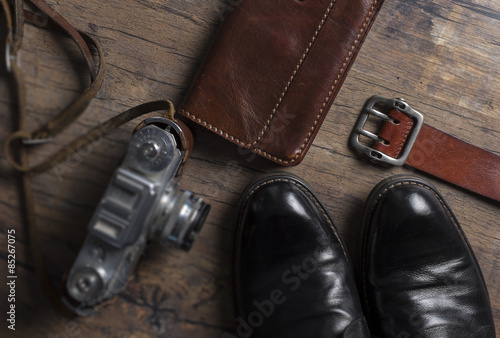Black shoes, film camera and wallet on the wooden table