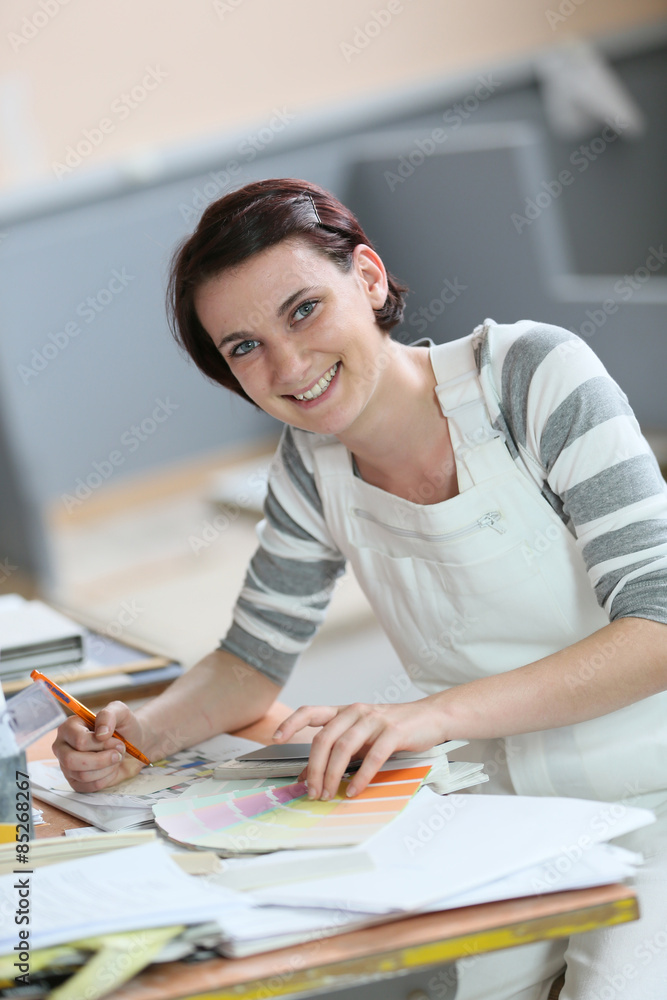 Young woman painter sitting at working table