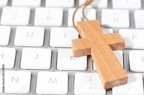 Yellow christian cross necklace on white modern computer keyboar photo