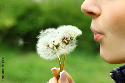 Fototapeta Naklejka Na Ścianę i Meble -  The girl blows away dandelion on nature