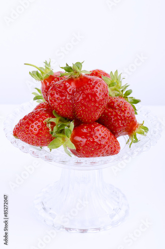 Transparent glass bowl with strawberries on white background