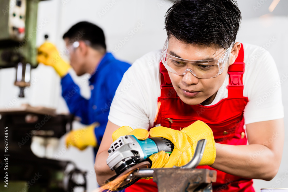 Two industrial workers in Asian metal factory Two industrial workers in Asian metal factory