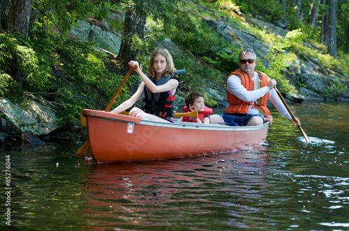family paddling a canoe on a wilderness lake