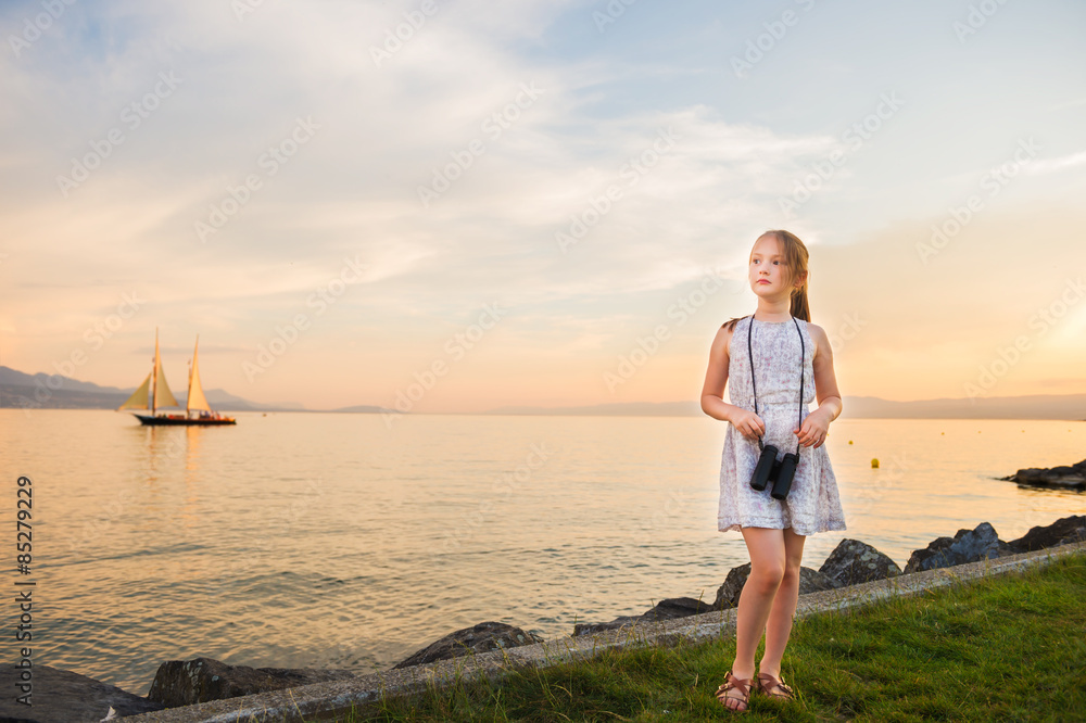 Outdoor portrait of a cute little girl playing by the lake on a nice warm evening