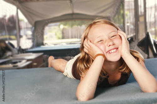 Young girl relaxing on the bed in a tent trailer