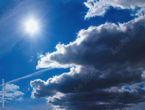 dark fluffy clouds in sunlight on background of blue sky