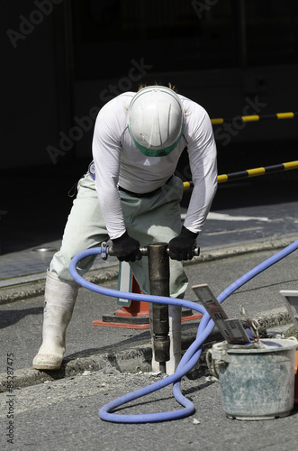 Worker use Jackhammer drilling cement concrete road, road repairing work