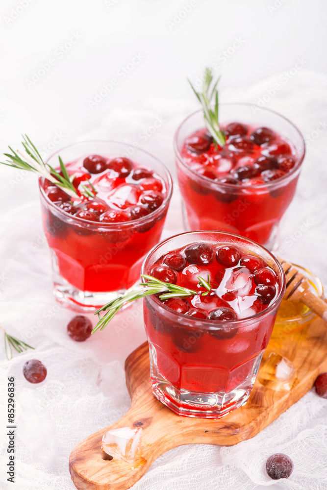 Cranberry cocktail with rosemary garnish, honey and soda on wooden background. Selective focus Cranberry cocktail with rosemary garnish, honey and soda on wooden background. Selective focus