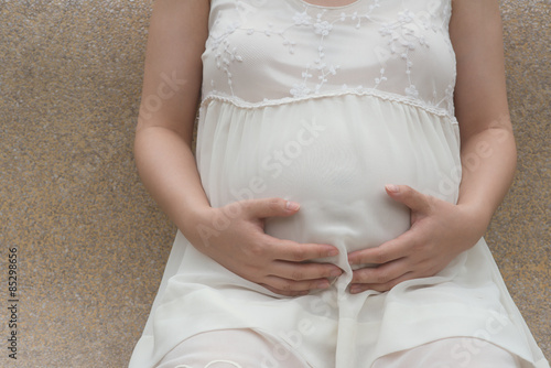 young pregnant woman putting hands on belly feeling her baby