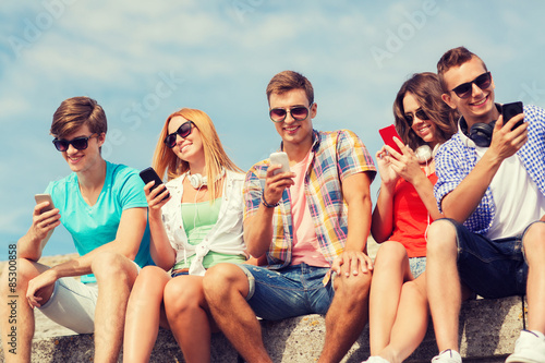 group of smiling friends with smartphones outdoors © Syda Productions