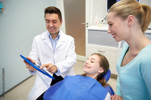 dentist showing tablet pc to girl and her mother