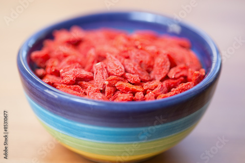 Dried goji berries in colored bowl on wooden table