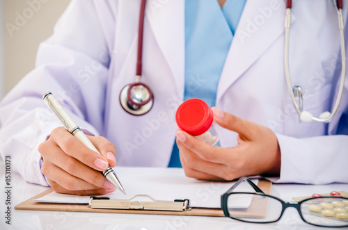 Canvas-taulu front view of doctor writing record on folder while holding medicine in office