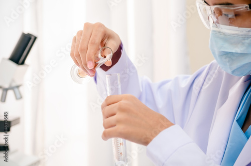 close up of scientist pouring chemical in flask for experiment 