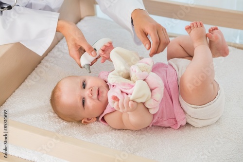 Beautiful cute baby girl with doctor taking temperature  photo