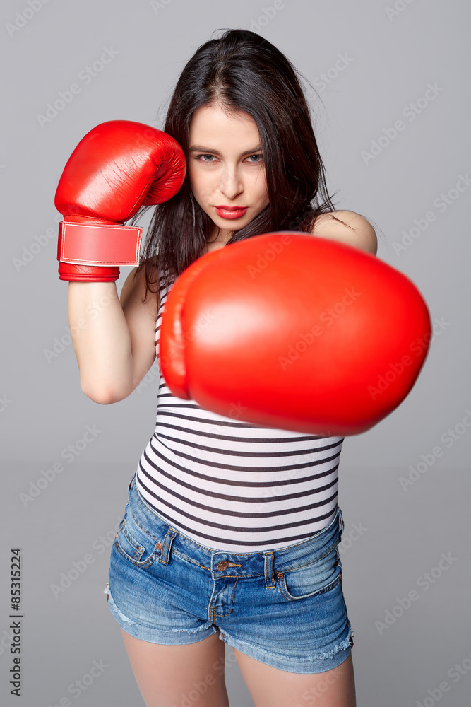 Determined attractive young woman wearing red boxing gloves thro Determined attractive young woman wearing red boxing gloves thro