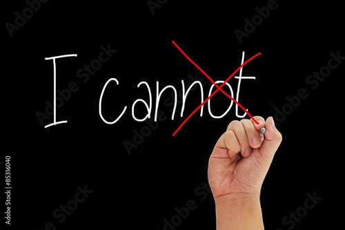 Hand with pen writing I cannot to give positive thinking and motivation isolated on black background.