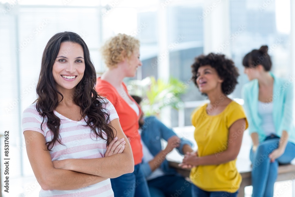 Obraz premium Smiling businesswoman with colleagues in background at office