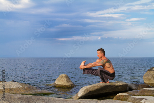 man practices yoga, gymnastics, acrobatics