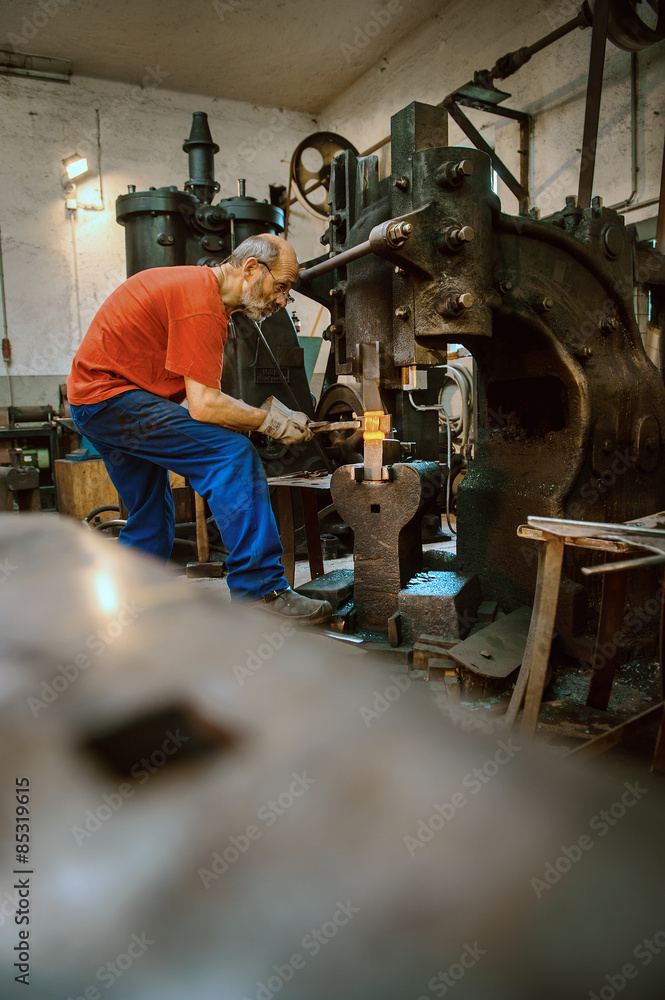 Senior blacksmith working in hammer mill Senior blacksmith working in hammer mill
