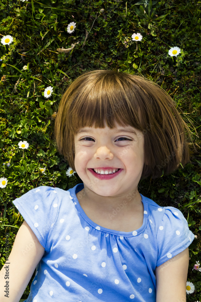 Portrait of happy little girl lying on a meadow Portrait of happy little girl lying on a meadow