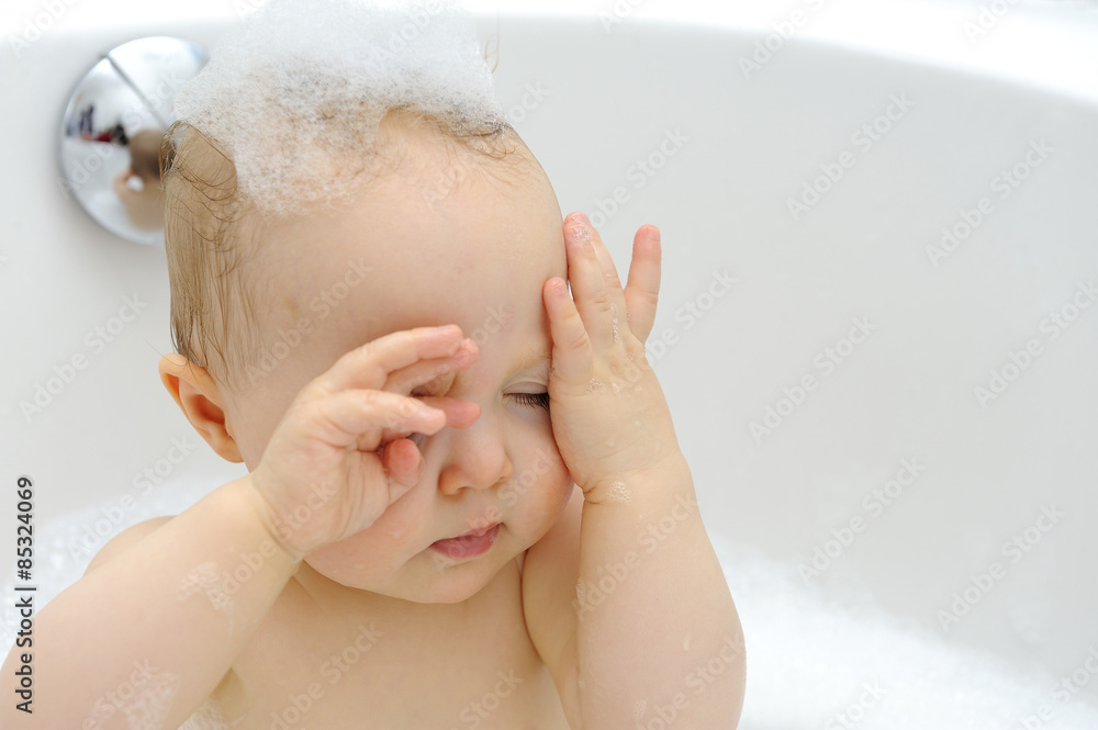 Baby girl in a bathtub wiping bath foam Baby girl in a bathtub wiping bath foam