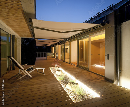 One family house, wooden terrace with awnings in the evening photo