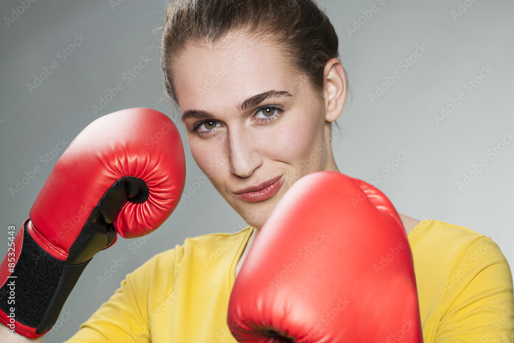 smiling young woman showing her fists in boxing gloves for female-male concept smiling young woman showing her fists in boxing gloves for female-male concept