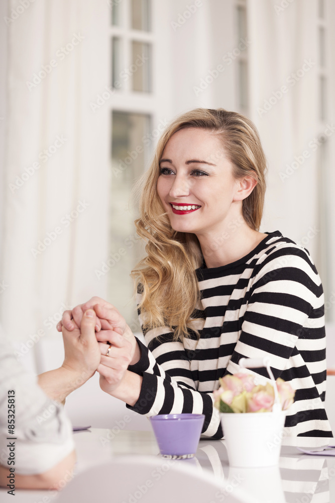 Smiling blond woman sitting in a coffee holding hands Smiling blond woman sitting in a coffee holding hands