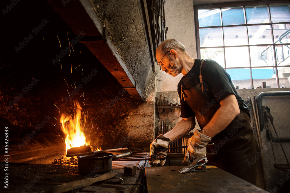 Senior blacksmith working in hammer mill Senior blacksmith working in hammer mill