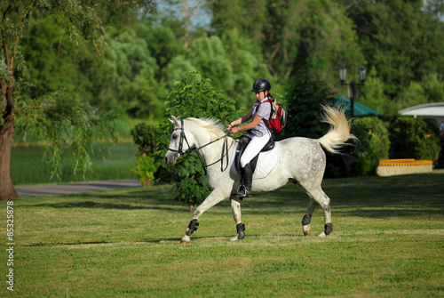 Beauty girl rides horseback in evening park