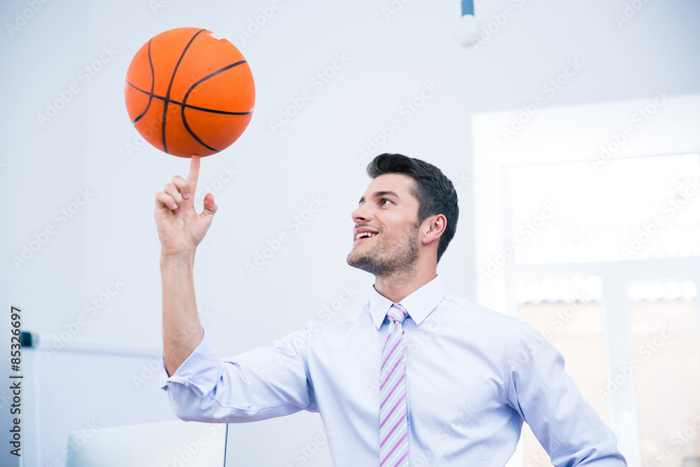 Smiling businessman spining ball in office