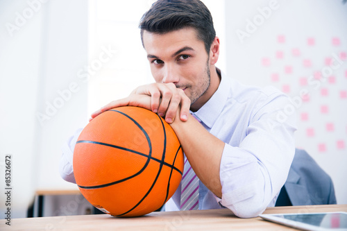Handsome businessman sitting at the table with ball