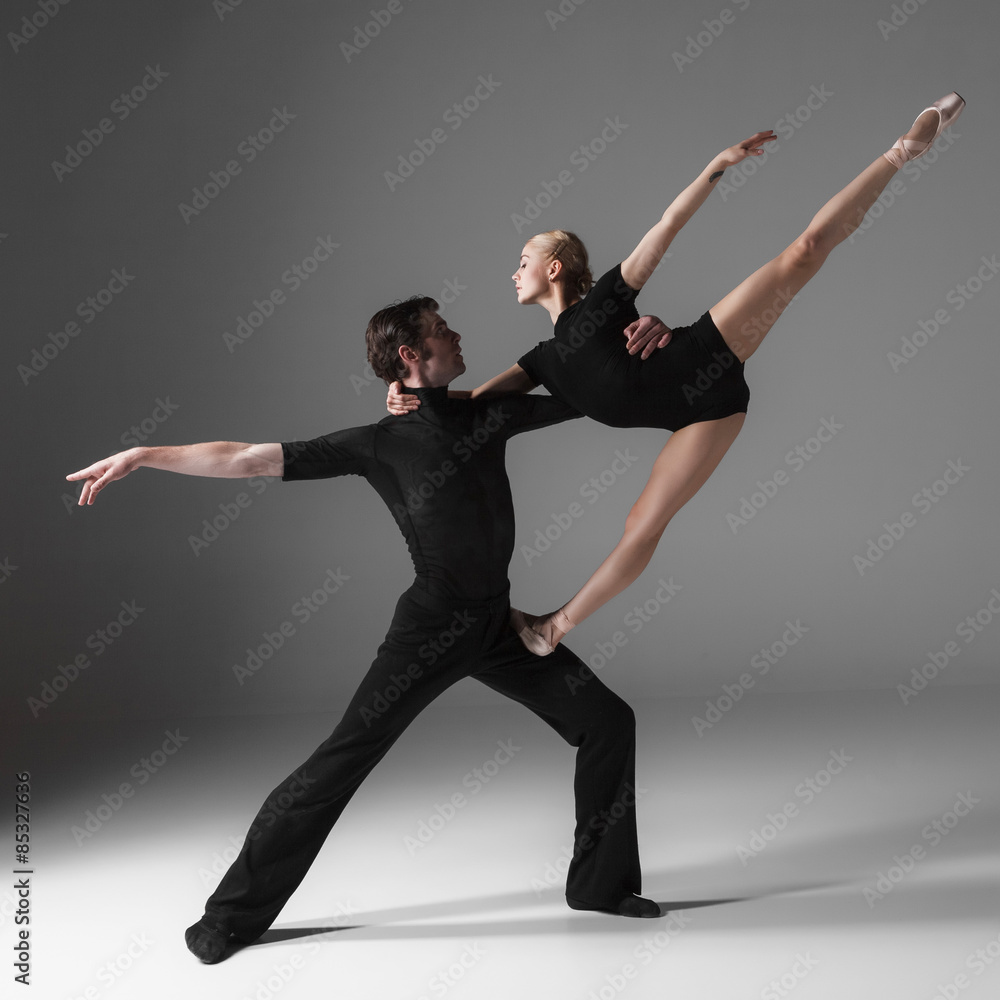 Obraz premium two young modern ballet dancers on gray studio background